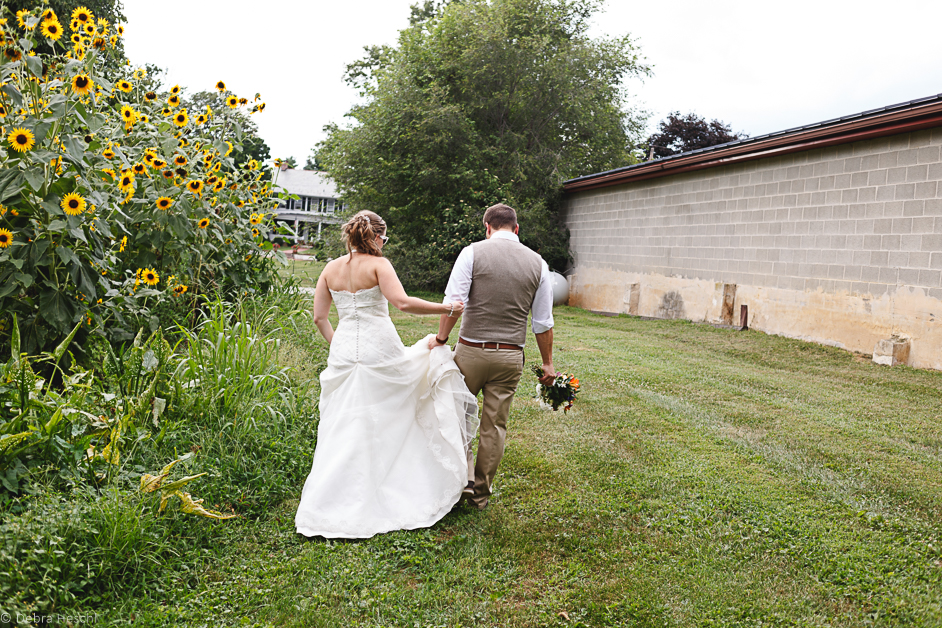 a bride & groom walking in a field