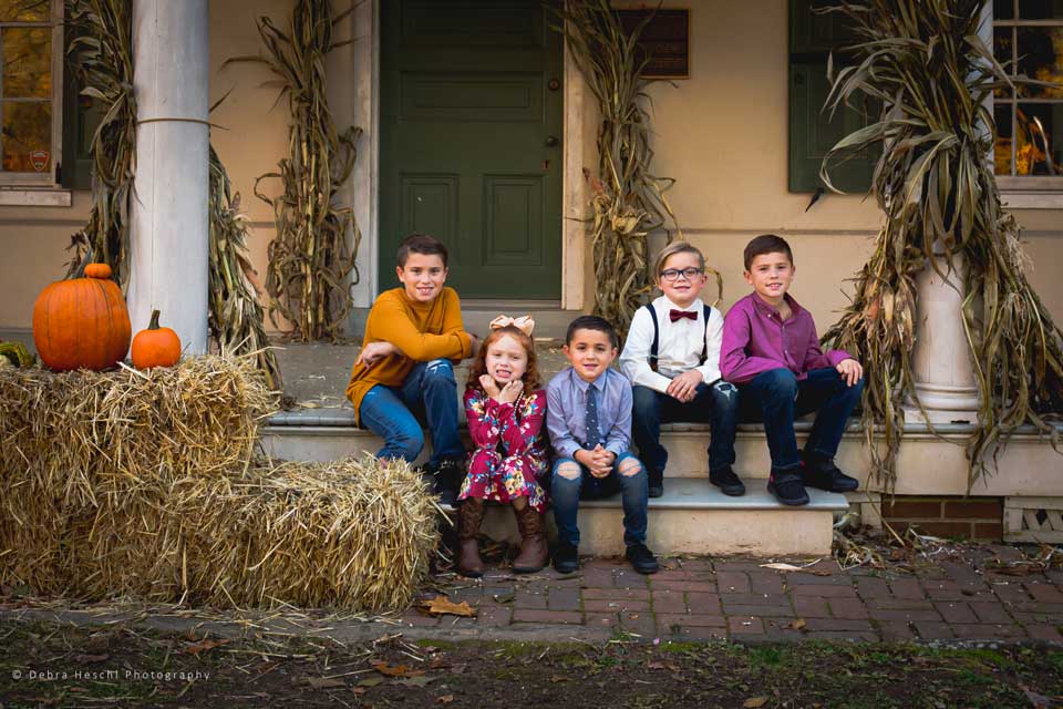 four boys & one girl posing for a photo on steps of a farmhouse
