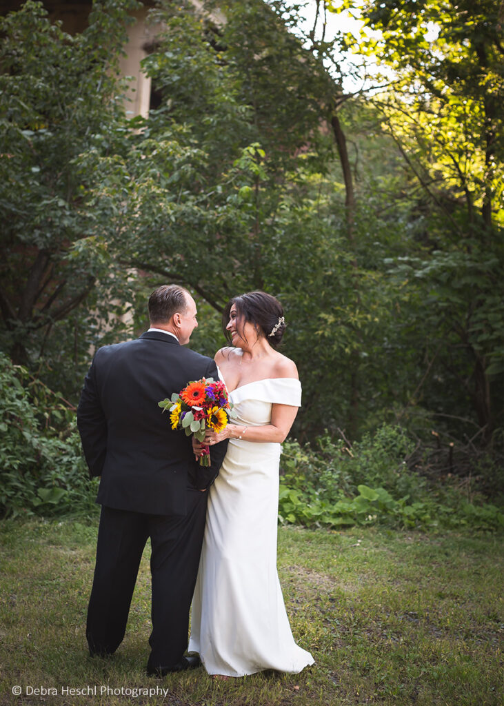 Bride and groom embracing and smiling at each other surrounded by greenery at their Sanatoga PA wedding.