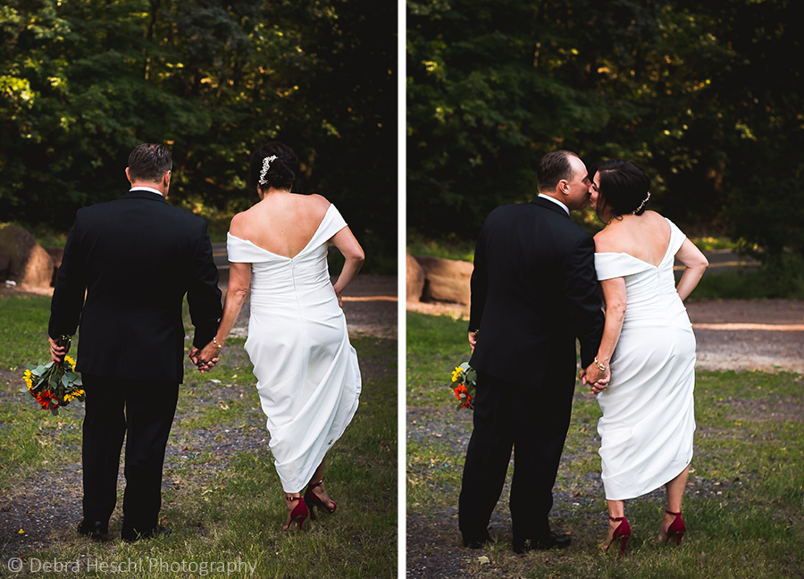 Bride and groom holding hands walking down a wooded path and sharing a kiss at their Sanatoga PA wedding.