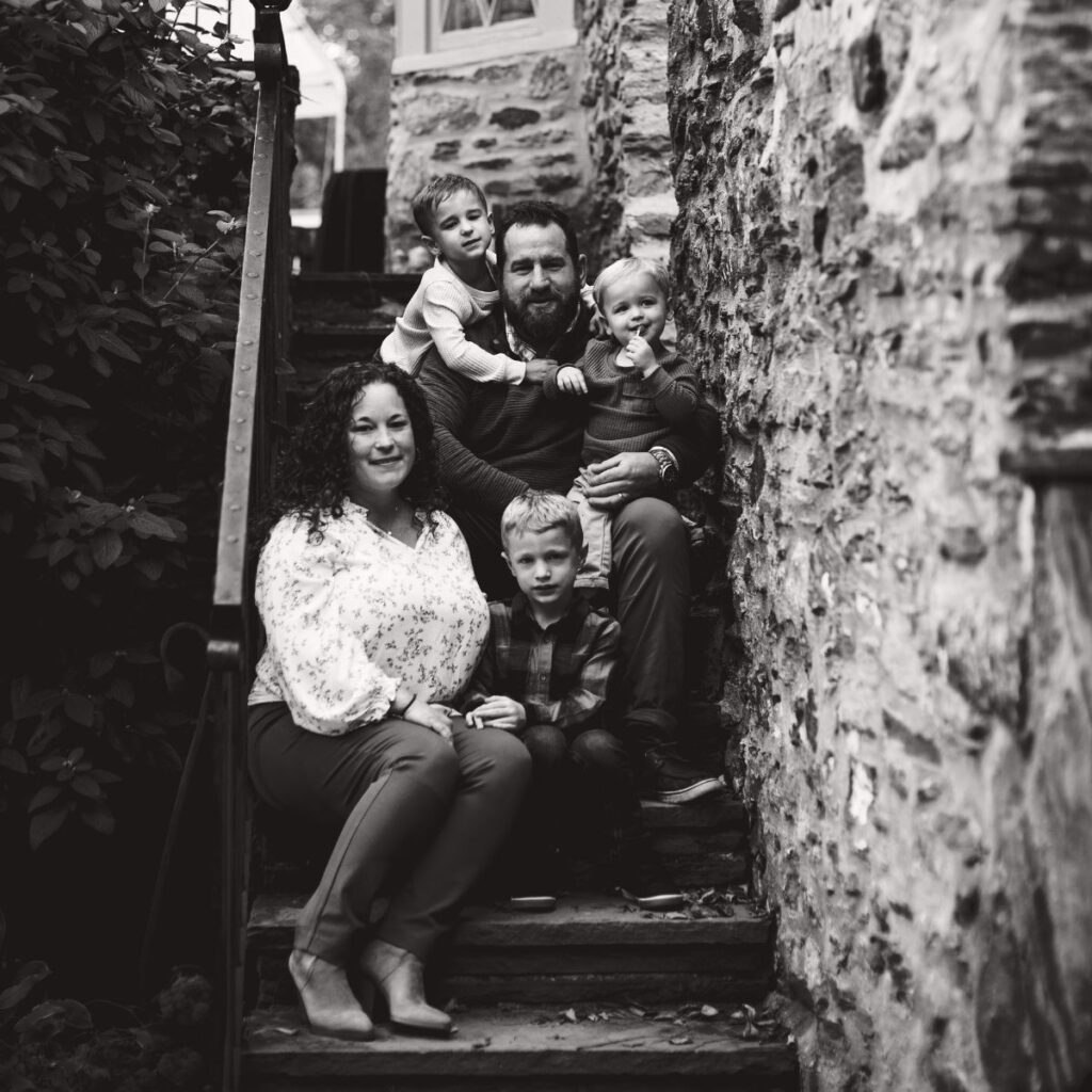 Black and white family portrait of the Fulginiti family sitting on a stone staircase at Harriton House in Bryn Mawr, PA.