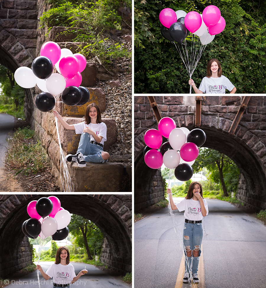Teen girl holding pink, black, and white balloons near a stone arch bridge for her 13th birthday photo session in Bridgeport, PA.