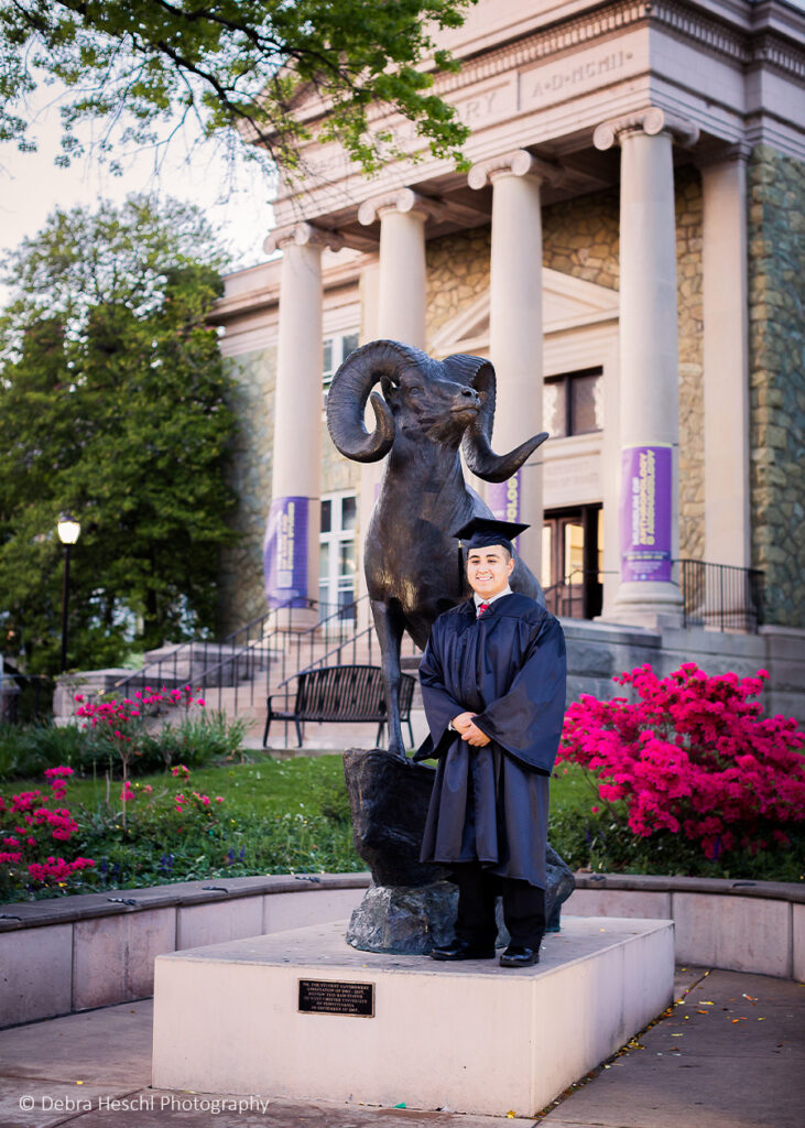 A college off Will posing in front of the elk statue at the school of West Chester University library.