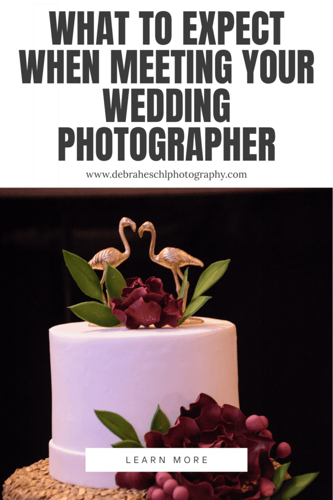 Wedding cake with gold flamingo toppers and burgundy flowers against a dark background. Text above reads "What to Expect When Meeting Your Wedding Photographer."