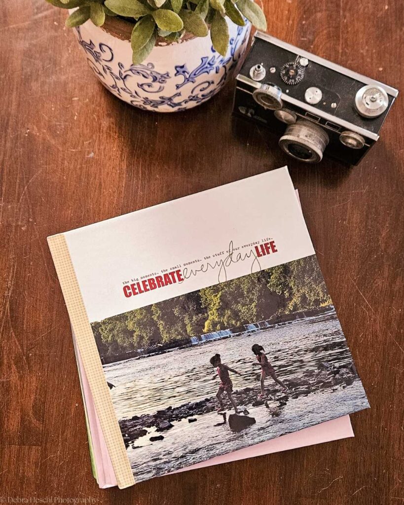 Printed photo album with family memories and vintage camera on wooden table