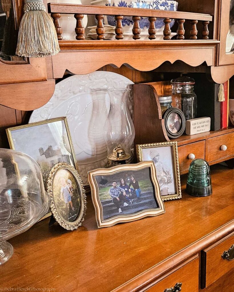 Framed family photos displayed on a wooden hutch showing printed memories in the home