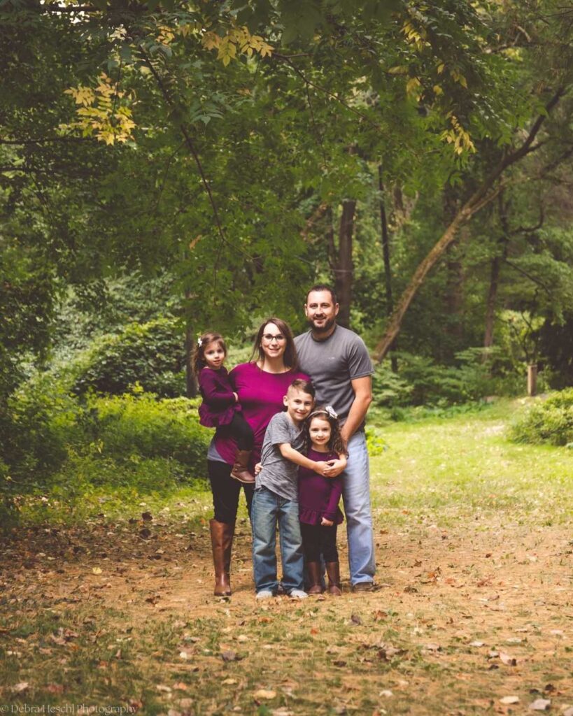 Family of five posing on a wooded trail during a fall kids photo session.