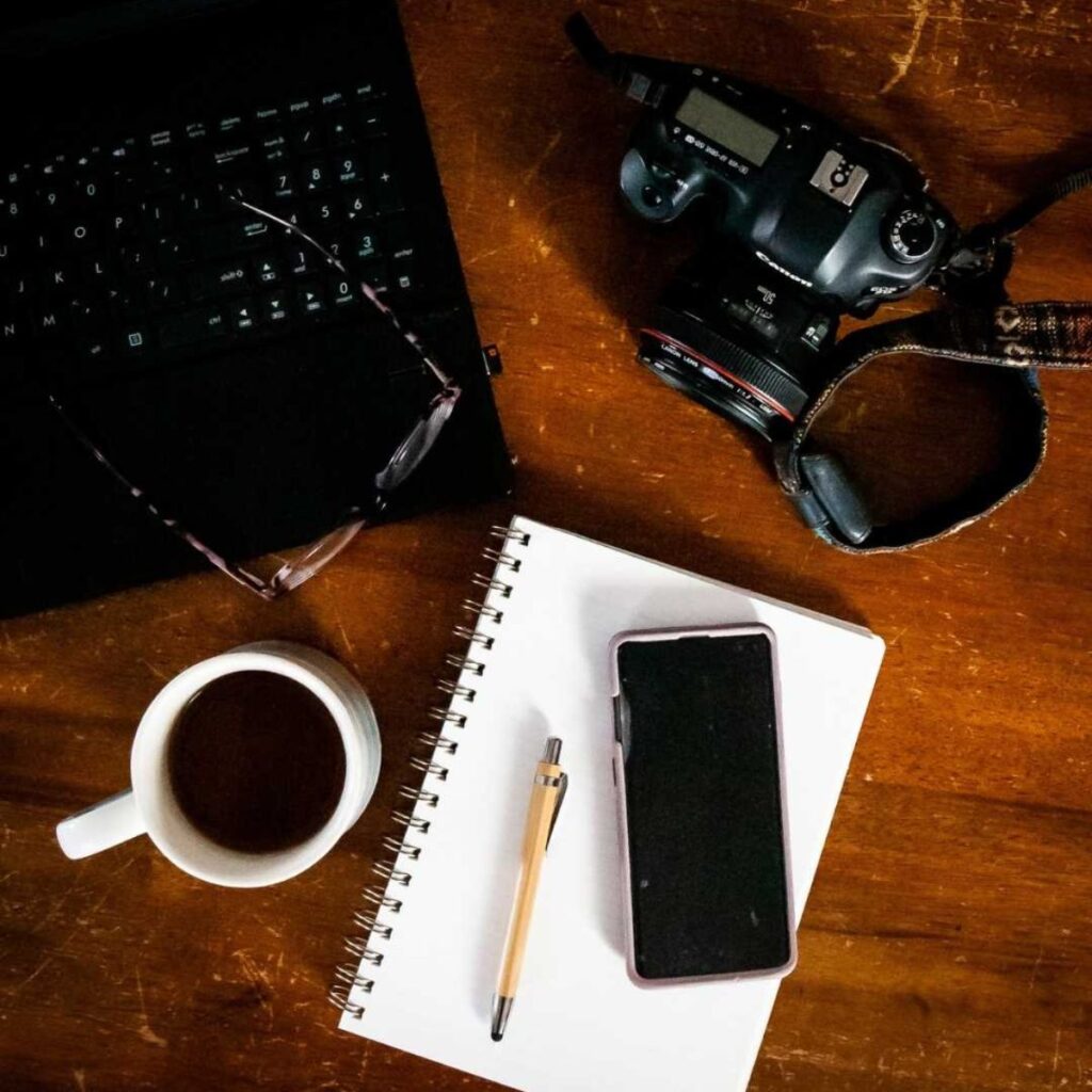 Camera, laptop, notebook, and coffee on the desk for photography blogging workflow