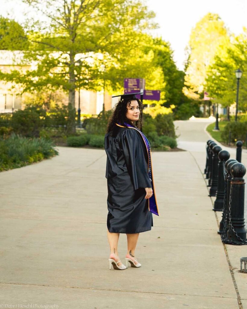 West Chester University Respiratory Therapy graduate walking campus pathway in cap and gown.