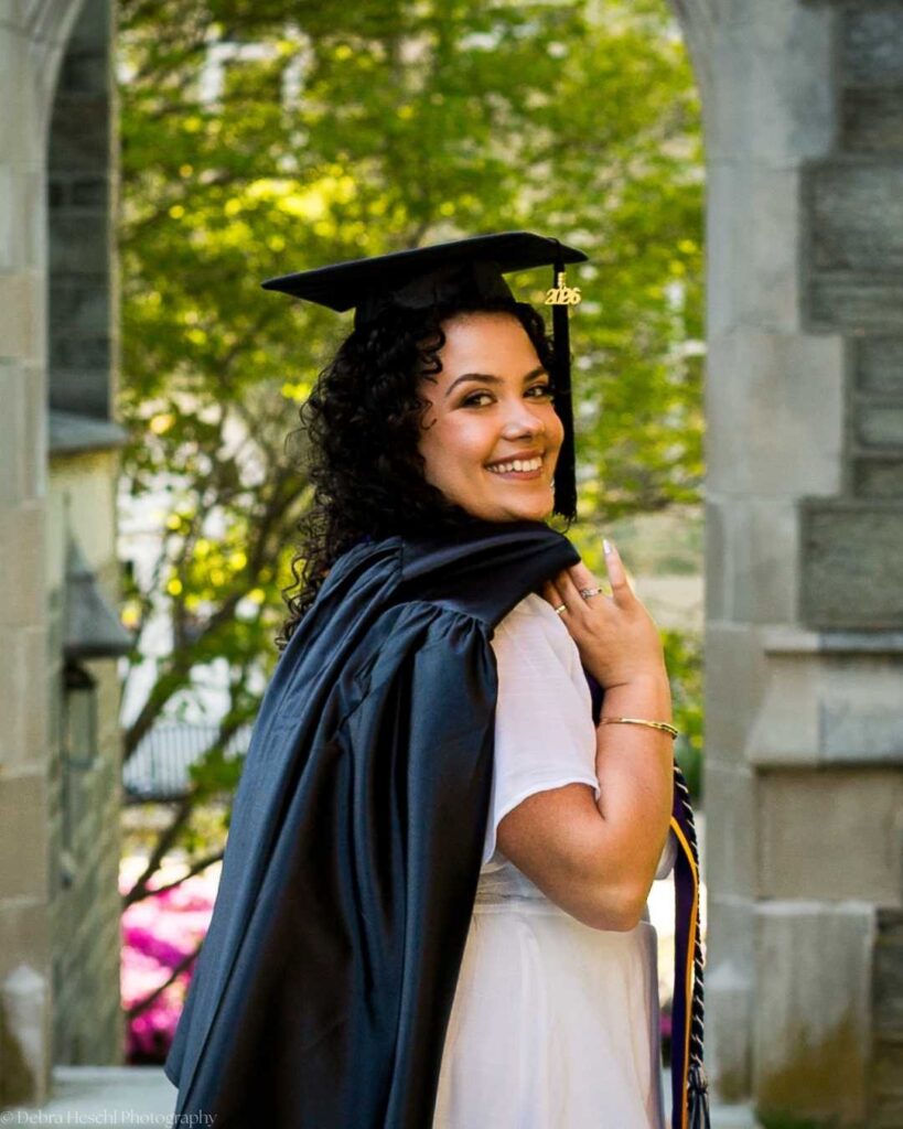 West Chester University Respiratory Therapy graduate smiling under stone archway in cap and gown