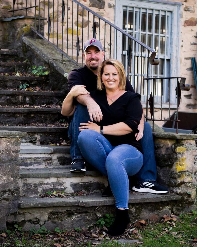 Couple sitting together on historic stone steps during a family portrait session at Manor House of Prophecy Creek in Blue Bell, Pennsylvania.