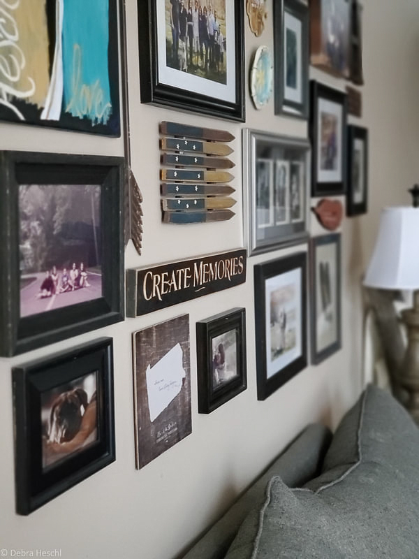 Close-up angle of a mixed frame gallery wall with vintage decor, wooden signs, and family photos.