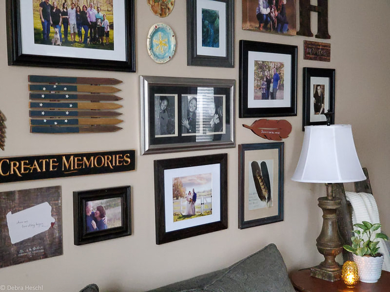 Mixed frame gallery wall featuring a "Create Memories" sign, black and white family photos, and feather art.