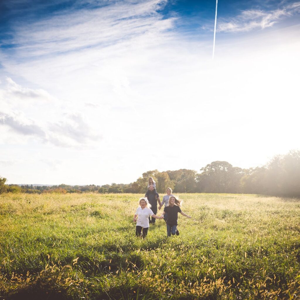 Family laughing and running through a golden field, a portrait moment worth backing up forever.
